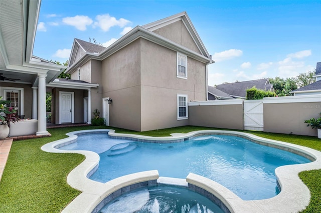view of swimming pool featuring a gate, a pool with connected hot tub, fence, and ceiling fan