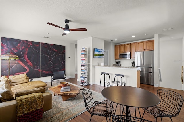 living room with dark wood-style flooring, a ceiling fan, recessed lighting, baseboards, and a textured ceiling