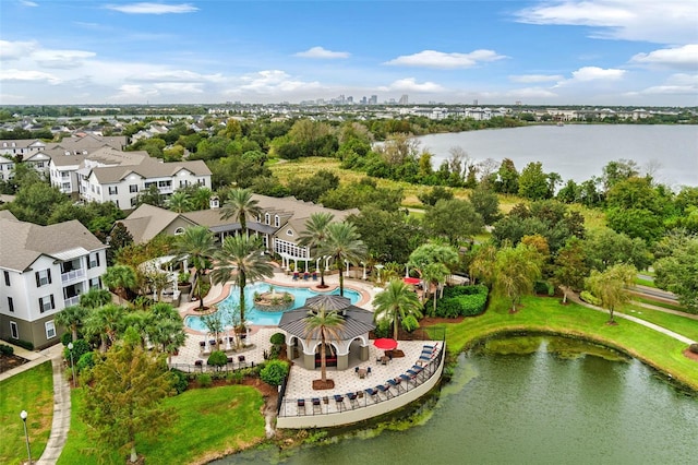 bird's eye view of a pool, a nearby body of water, and a tree filled landscape