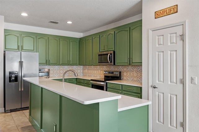 570 Cascading Creek Ln, Winter Garden, FL 34787 - kitchen with stainless steel appliances, green cabinets, a center island with sink, light countertops, and decorative backsplash