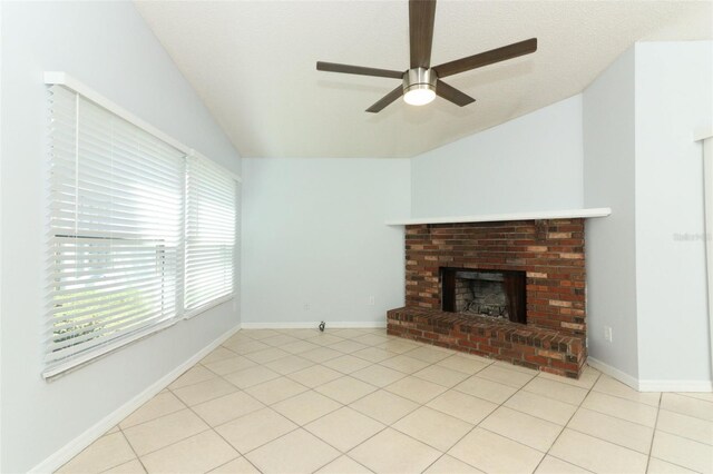 unfurnished living room featuring vaulted ceiling, ceiling fan, a fireplace, light tile patterned floors, and baseboards