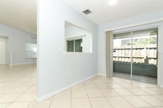 spare room with lofted ceiling, light tile patterned floors, and baseboards