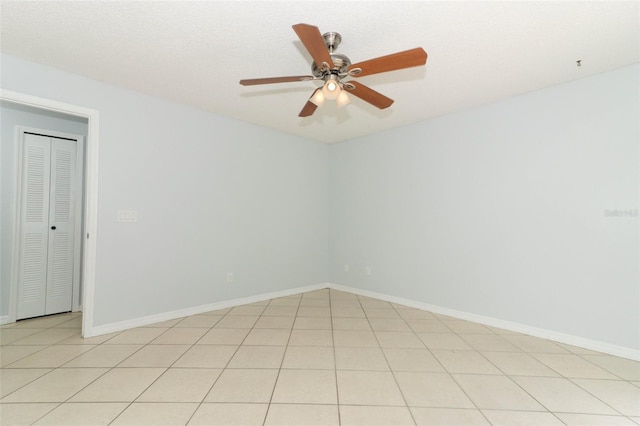 empty room featuring ceiling fan, baseboards, and light tile patterned floors