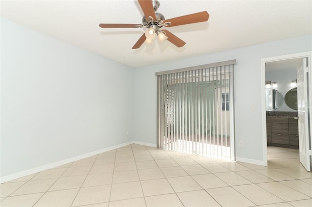 unfurnished room featuring ceiling fan, light tile patterned floors, and baseboards