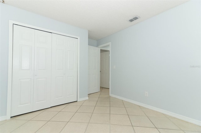 unfurnished bedroom with baseboards, a closet, and light tile patterned floors