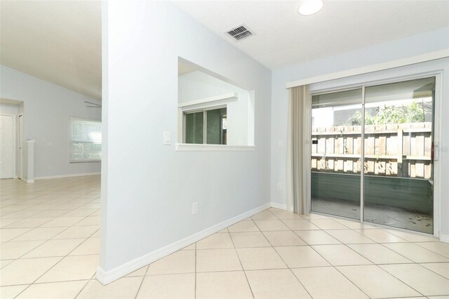 spare room featuring light tile patterned floors, vaulted ceiling, and baseboards