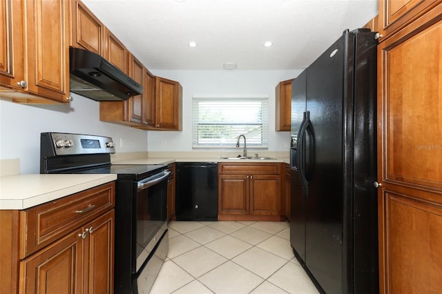 kitchen with black appliances, under cabinet range hood, a sink, brown cabinets, and recessed lighting