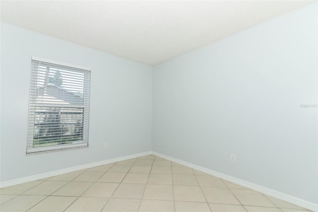 empty room with baseboards and light tile patterned floors