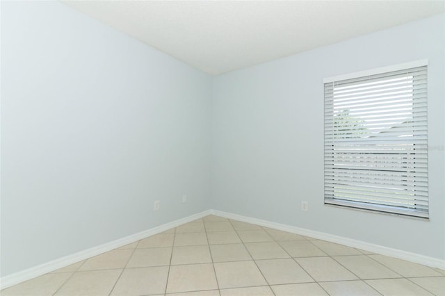 spare room with baseboards and light tile patterned flooring