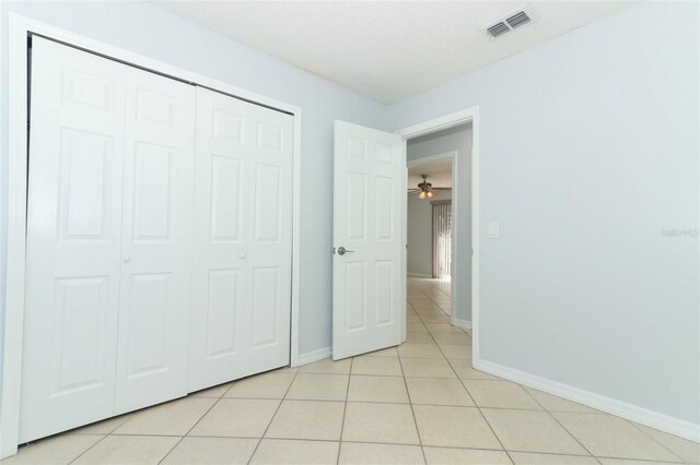 unfurnished bedroom featuring light tile patterned floors, baseboards, and a closet
