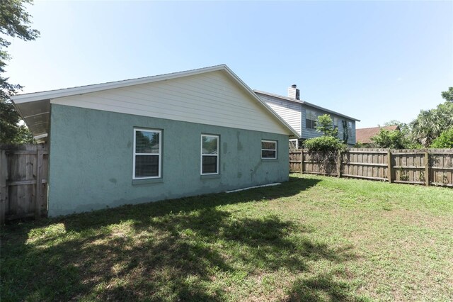 rear view of house with stucco siding and a chimney