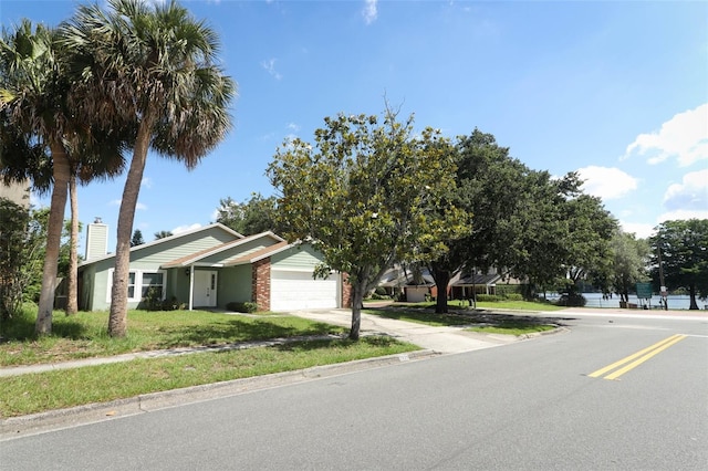 view of front of home featuring an attached garage, concrete driveway, brick siding, and a front yard