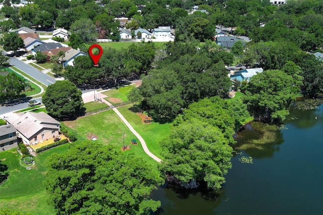 view of property location featuring a nearby body of water, nearby suburban area, and a tree filled landscape