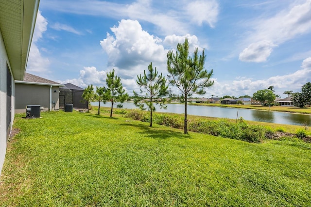 view of green lawn featuring a water view and central AC