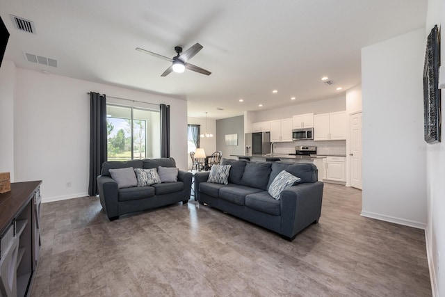 living area with baseboards, a ceiling fan, recessed lighting, and a chandelier