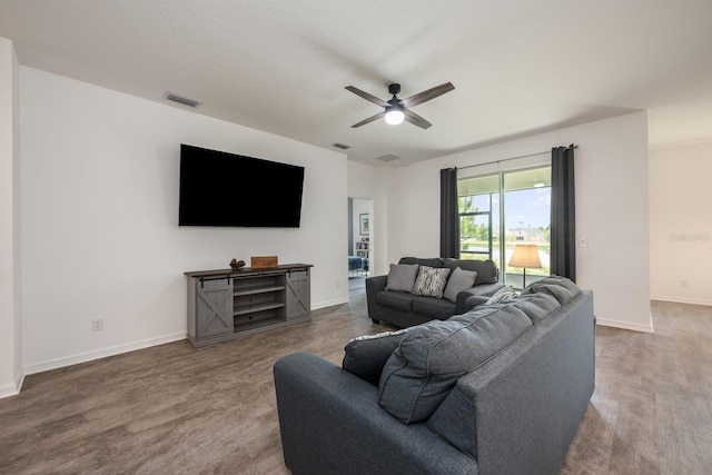 living room with a ceiling fan, baseboards, and wood finished floors