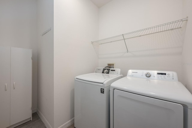 clothes washing area with separate washer and dryer and baseboards