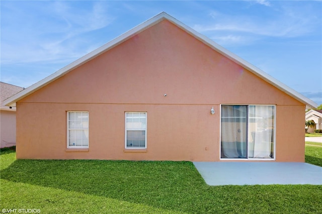 back of property featuring a yard, stucco siding, and a patio