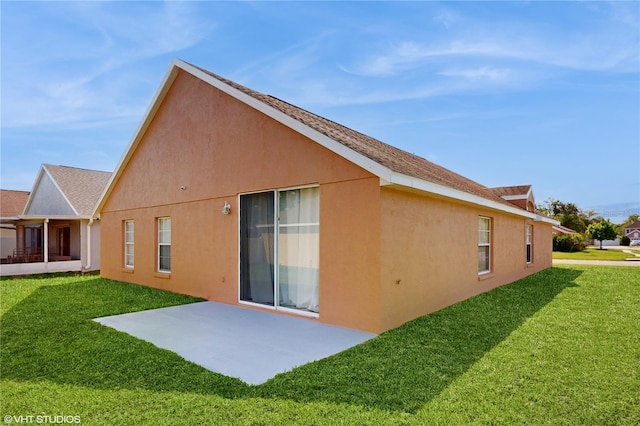rear view of property featuring stucco siding, a patio area, and a yard