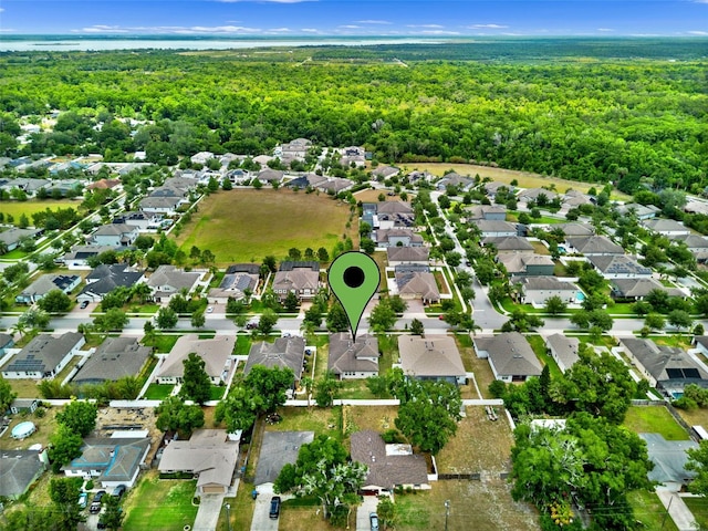 aerial view of property and surrounding area featuring a forest and nearby suburban area