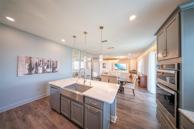 1631 Pontiff Pl, Davenport, FL 33896 - kitchen featuring a sink, stainless steel appliances, gray cabinets, open floor plan, and a kitchen island with sink