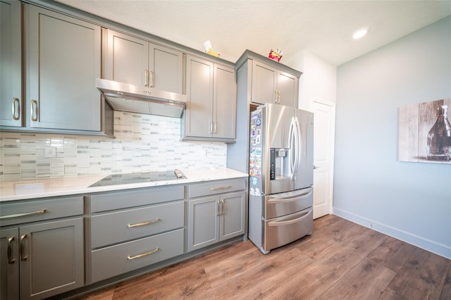 1631 Pontiff Pl, Davenport, FL 33896 - kitchen with stainless steel fridge, gray cabinets, black electric cooktop, under cabinet range hood, and light wood-style floors