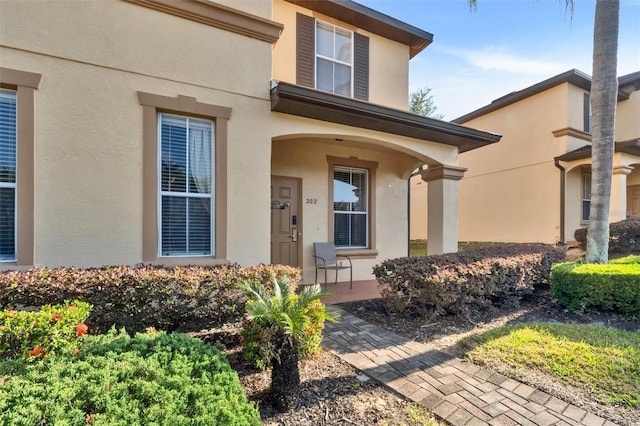 view of exterior entry featuring a porch and stucco siding