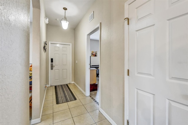 foyer entrance featuring light tile patterned floors, baseboards, and visible vents