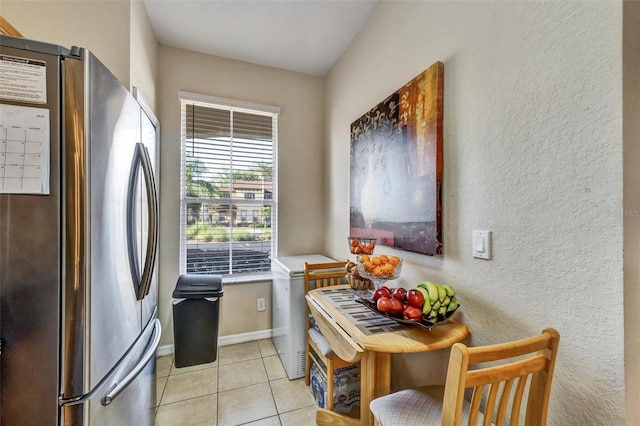 kitchen featuring freestanding refrigerator, a textured wall, light countertops, and light tile patterned floors