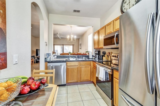 kitchen with visible vents, a sink, arched walkways, dark countertops, and stainless steel appliances