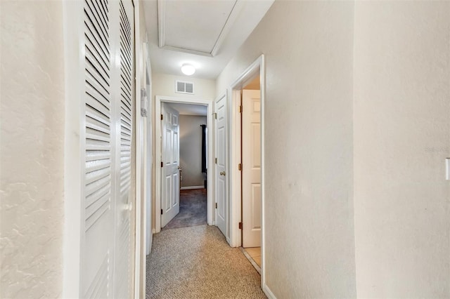 hall featuring light colored carpet and visible vents