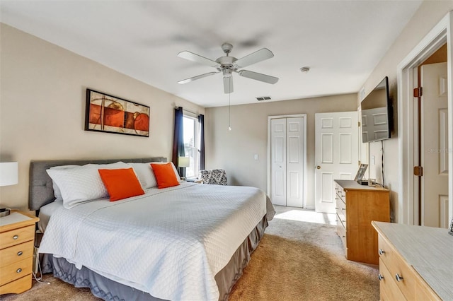 bedroom featuring a closet, light carpet, visible vents, and ceiling fan