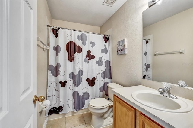full bathroom featuring toilet, vanity, visible vents, tile patterned floors, and a textured wall