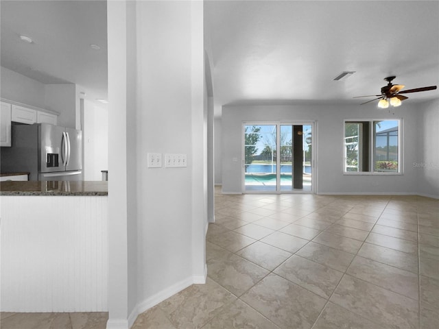 unfurnished living room with baseboards, ceiling fan, and light tile patterned floors