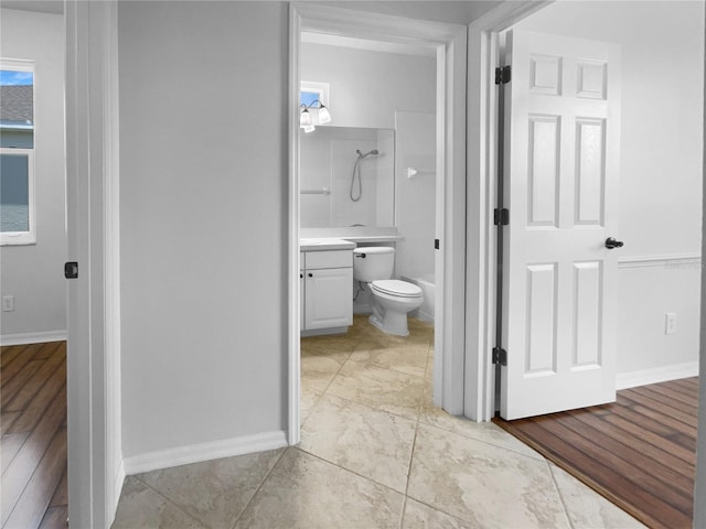 bathroom with toilet, a shower, vanity, and baseboards