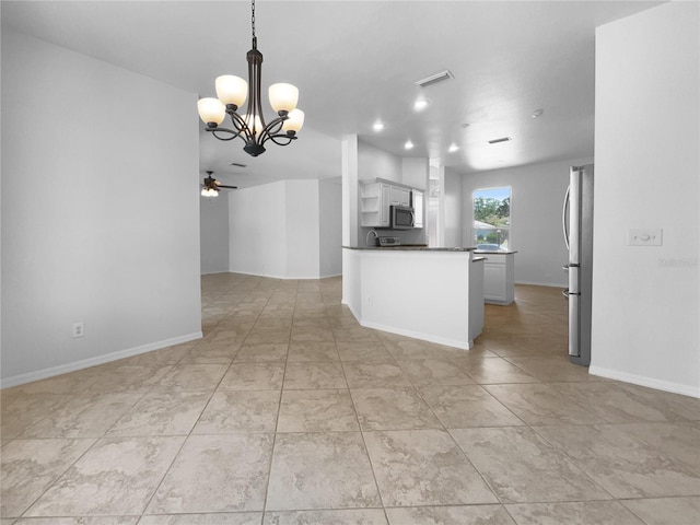 kitchen featuring appliances with stainless steel finishes, dark countertops, open floor plan, a ceiling fan, and a chandelier