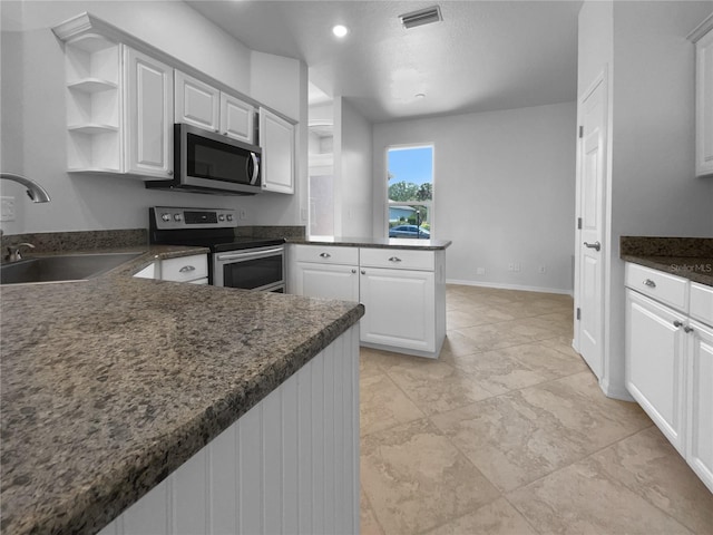 kitchen featuring stainless steel appliances, a sink, a peninsula, white cabinets, and recessed lighting