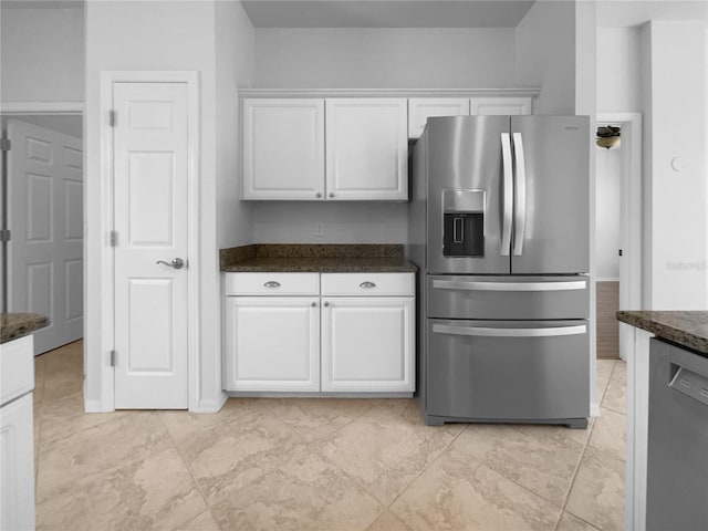 kitchen with stainless steel appliances, white cabinetry, and dark stone counters