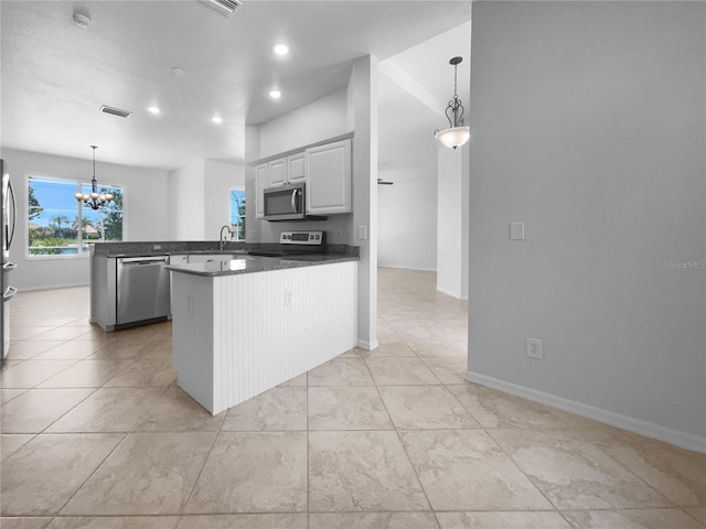 kitchen featuring stainless steel appliances, a peninsula, a chandelier, dark countertops, and recessed lighting