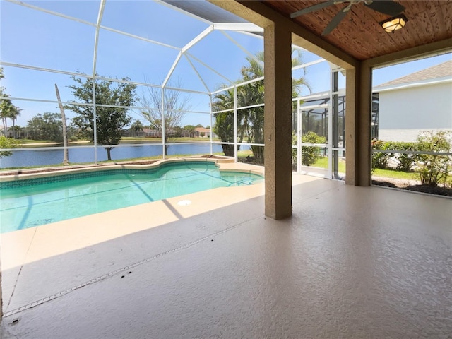 outdoor pool with a patio area, ceiling fan, glass enclosure, and a water view