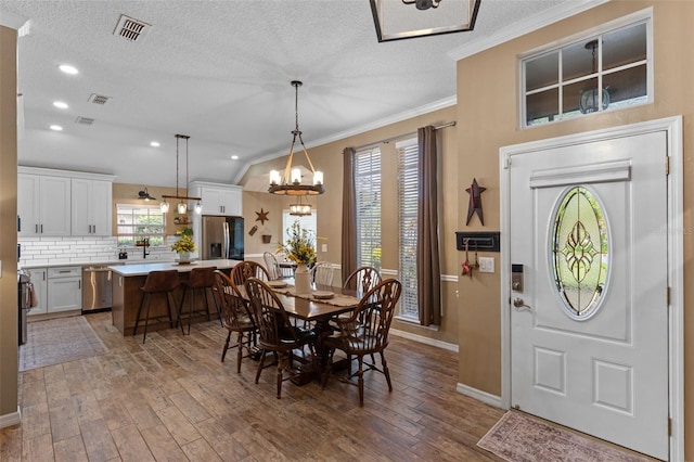 dining area featuring baseboards, an inviting chandelier, visible vents, crown molding, and wood finished floors