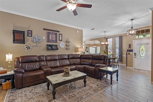 living room with wood finished floors, ceiling fan with notable chandelier, crown molding, a textured ceiling, and baseboards