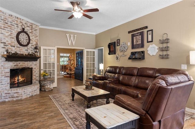 living area featuring ornamental molding, ceiling fan, a brick fireplace, and wood finished floors