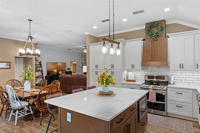 kitchen featuring visible vents, light wood finished floors, white cabinetry, a kitchen island, and appliances with stainless steel finishes