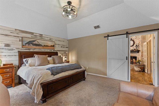 carpeted bedroom featuring lofted ceiling, a barn door, baseboards, visible vents, and wooden walls