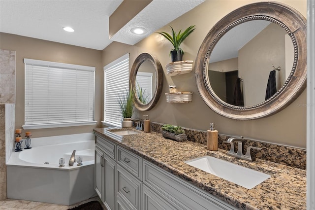 full bathroom with a bath, recessed lighting, double vanity, and a sink