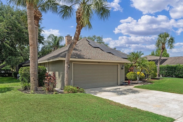 ranch-style house featuring a chimney, driveway, an attached garage, roof with shingles, and a front lawn