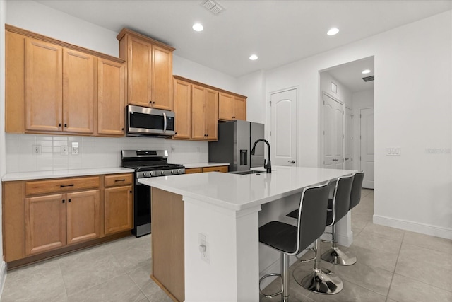 2524 Datura Loop, Saint Cloud, FL 34772 - kitchen featuring appliances with stainless steel finishes, an island with sink, light tile patterned floors, backsplash, and light countertops