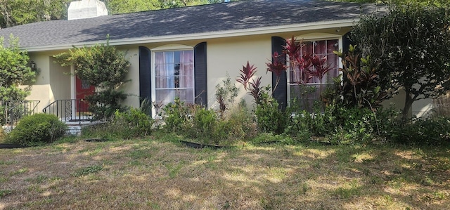 view of side of home featuring a shingled roof, stucco siding, and a chimney