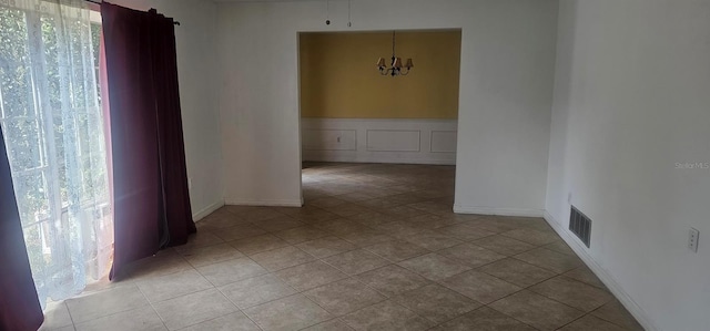 spare room with an inviting chandelier, light tile patterned flooring, baseboards, and visible vents